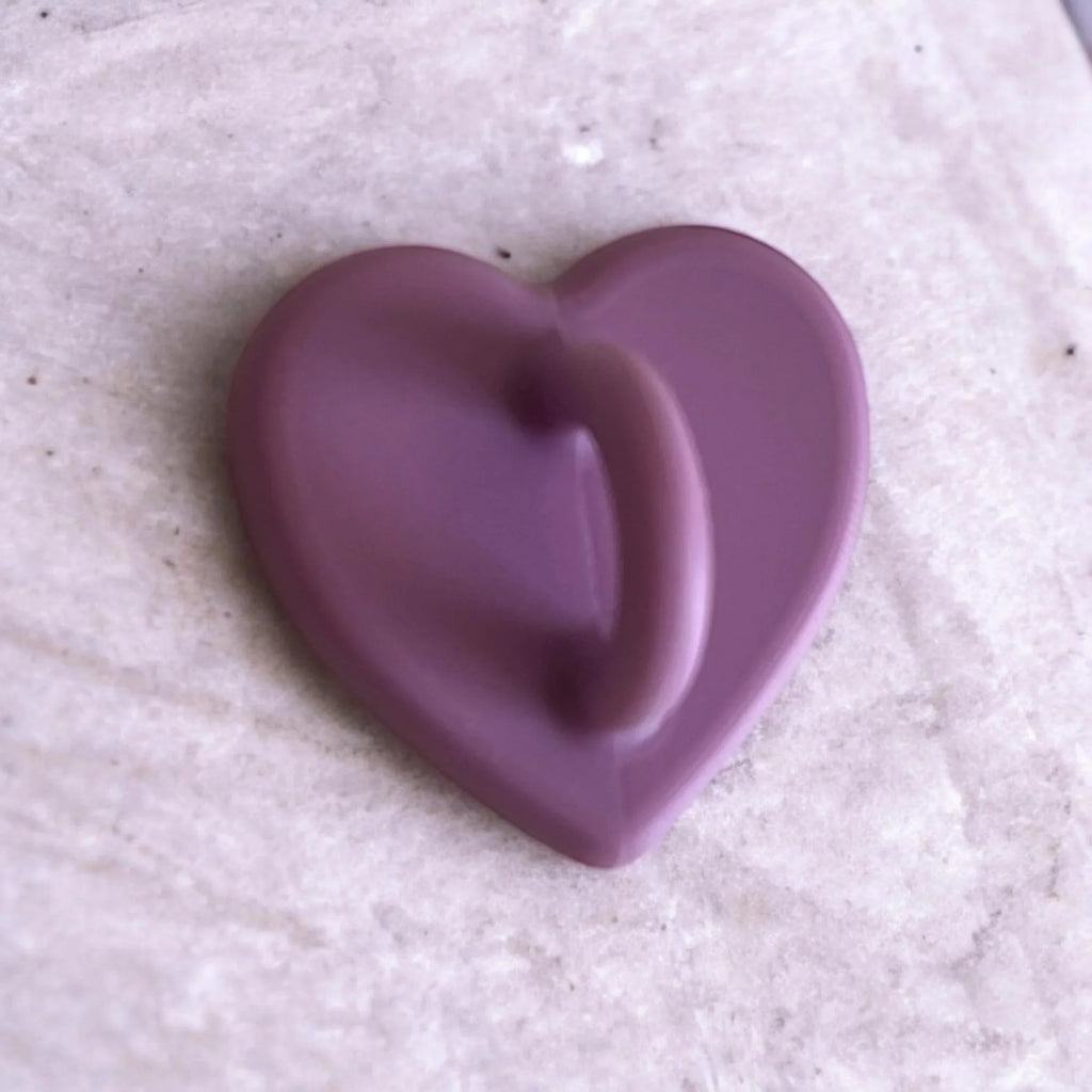 Purple heart-shaped soap bar on textured surface, gentle skincare