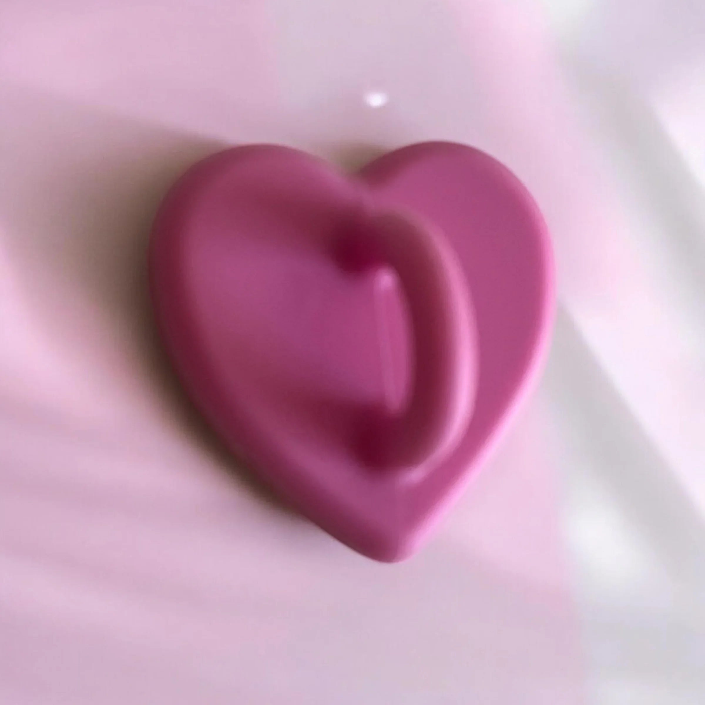 Pink heart-shaped soap bar on soft fabric background, romantic bath accessory