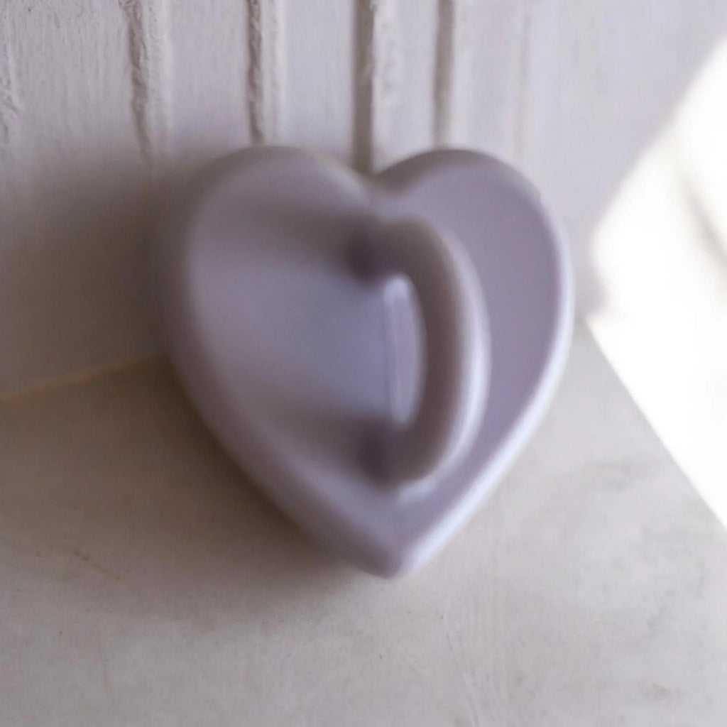 Soft purple heart-shaped ceramic dish on white wooden shelf, minimalist home decor accent