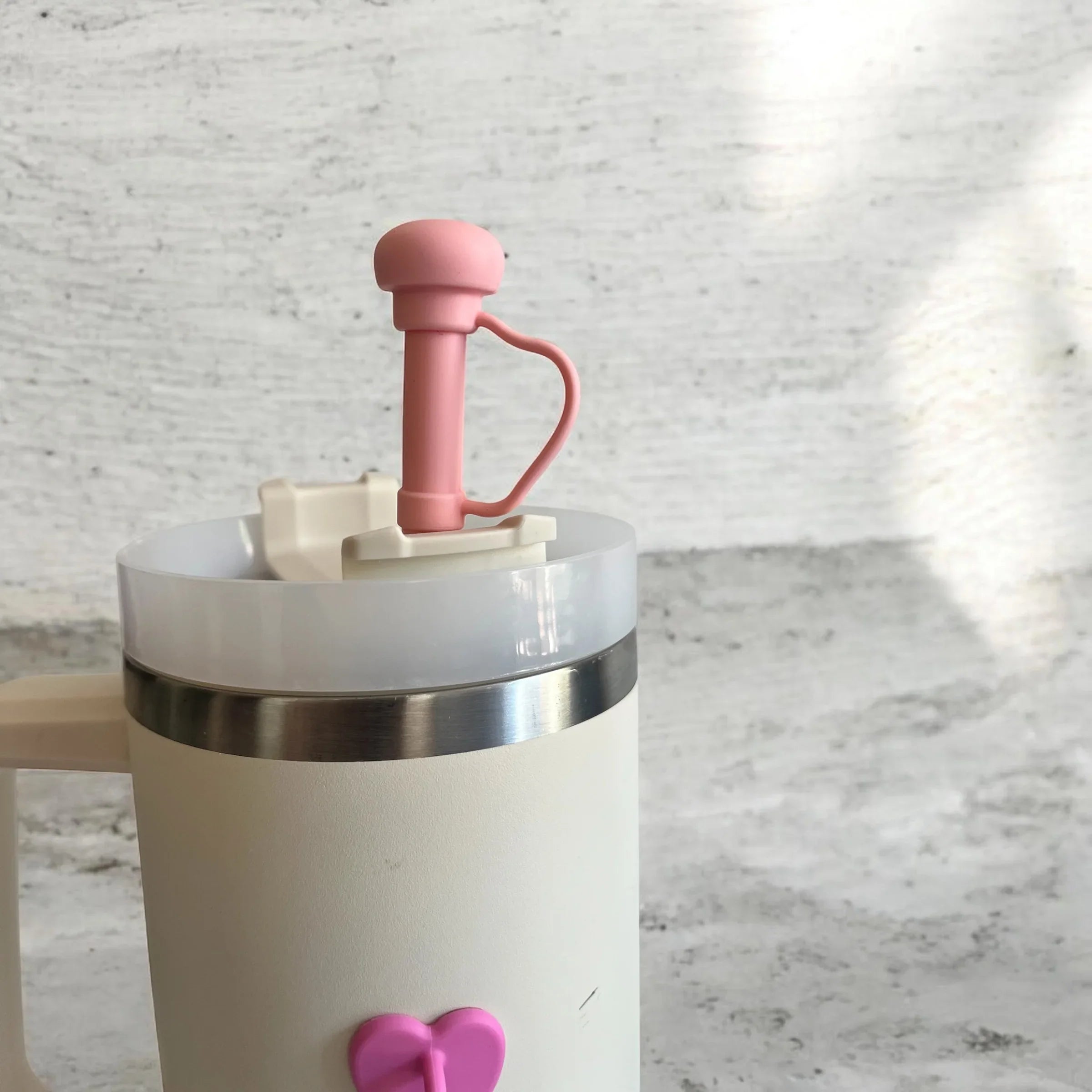 Pink-handled manual coffee grinder with heart accent on cream base, ideal for home brewing
