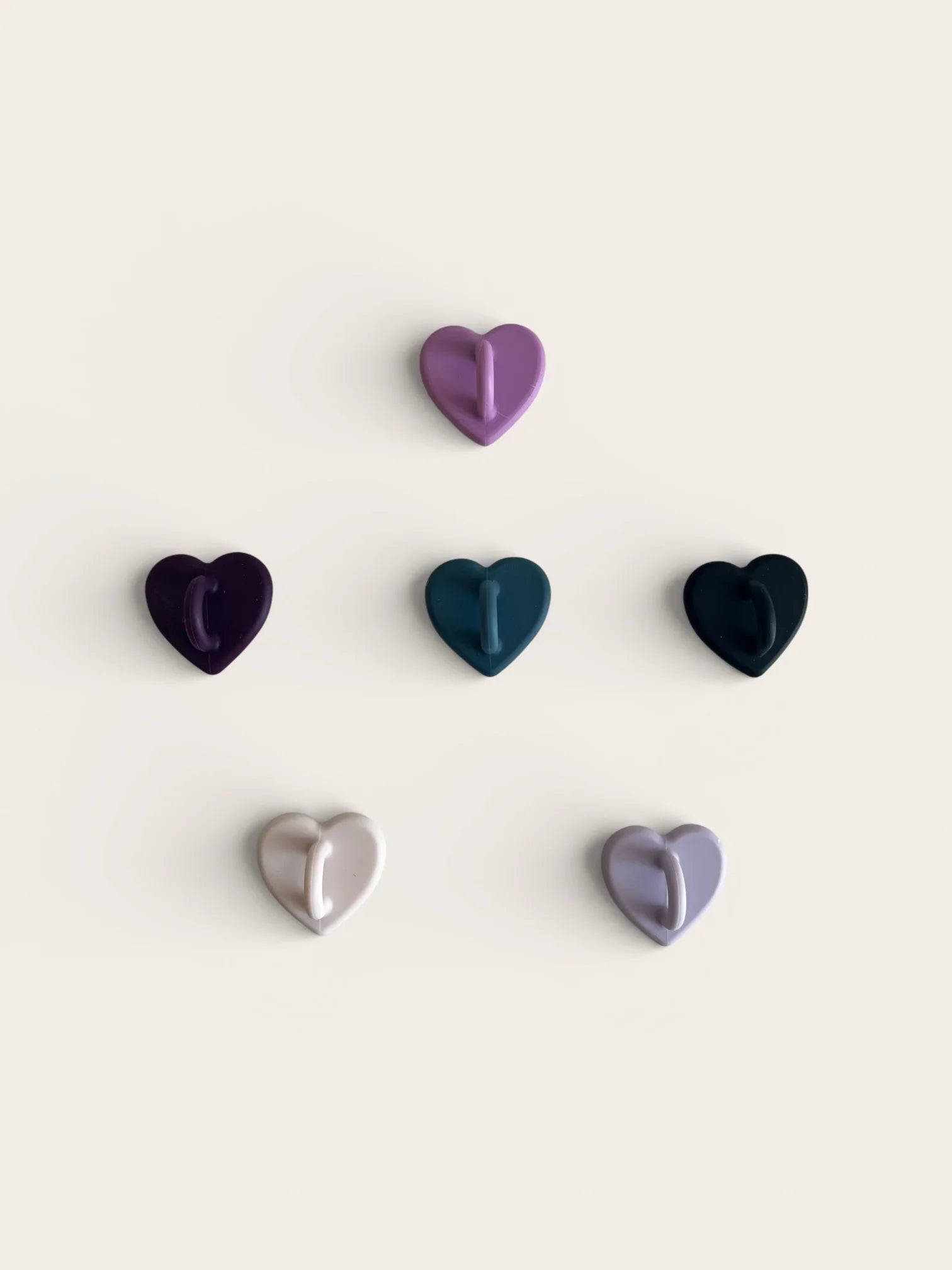 Set of heart-shaped wall hooks in purple, blue, black, and gray for home organization