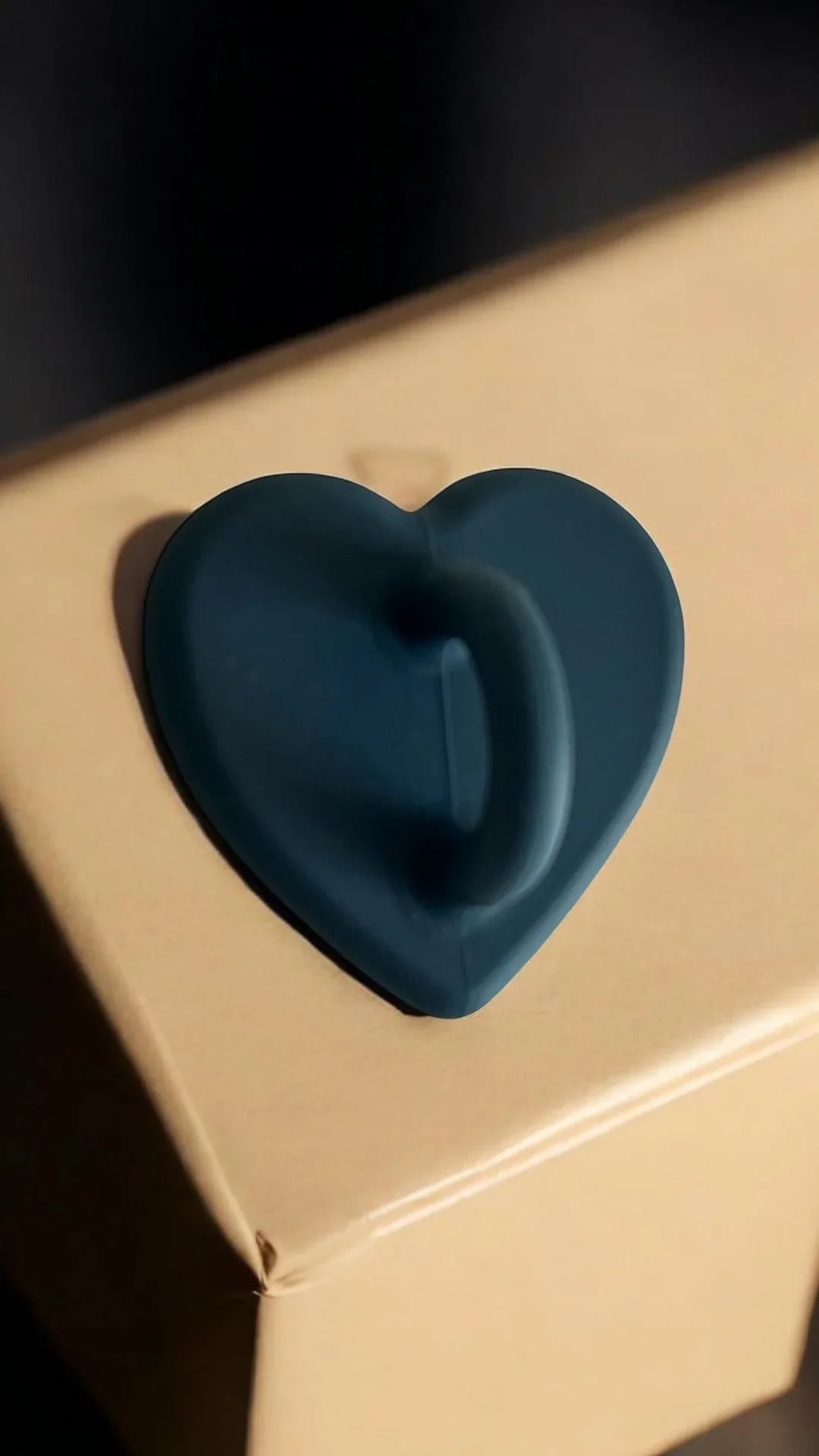 Dark blue heart-shaped silicone grip on cardboard box, ideal for easy handling and secure transport