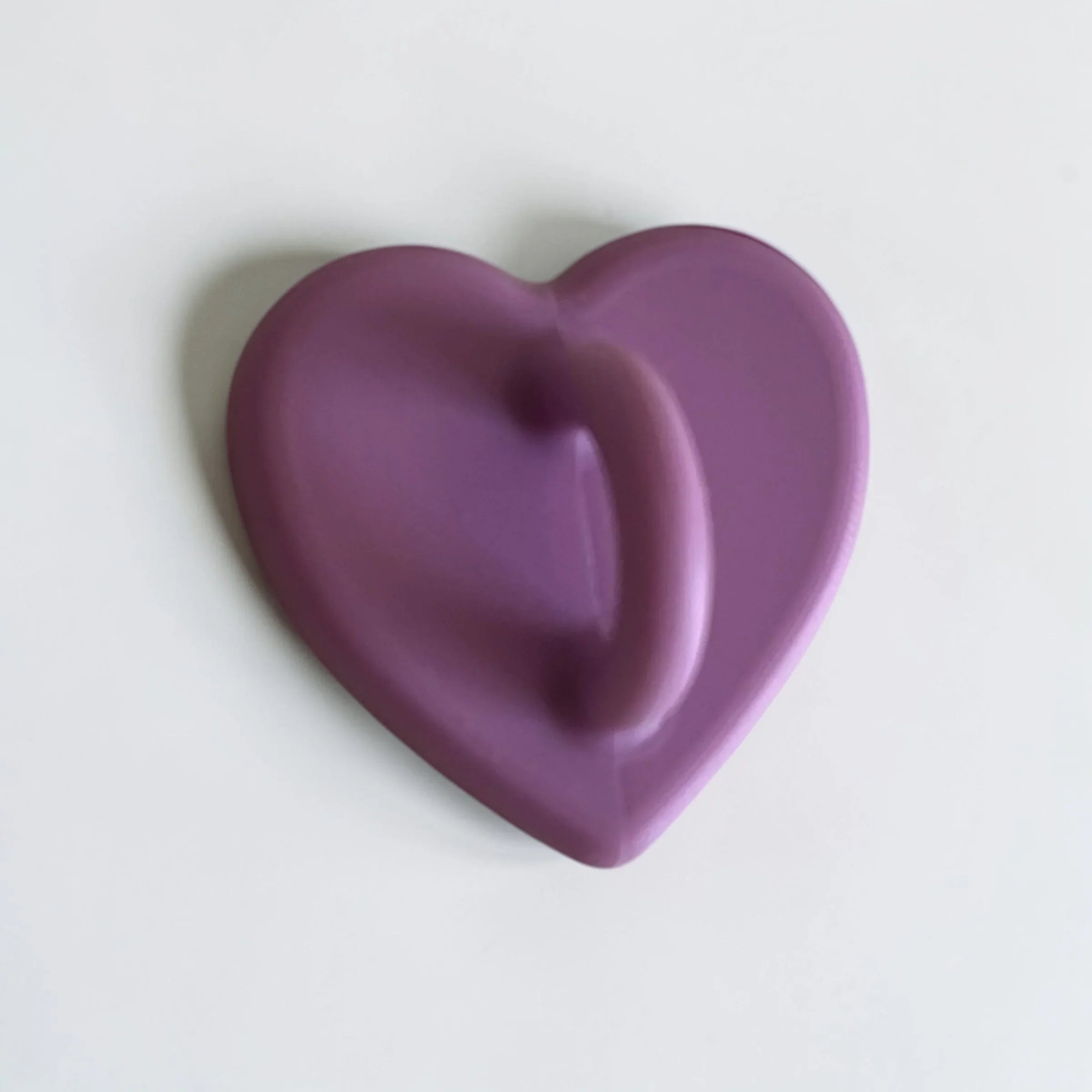 Purple heart-shaped object with smooth texture on white background