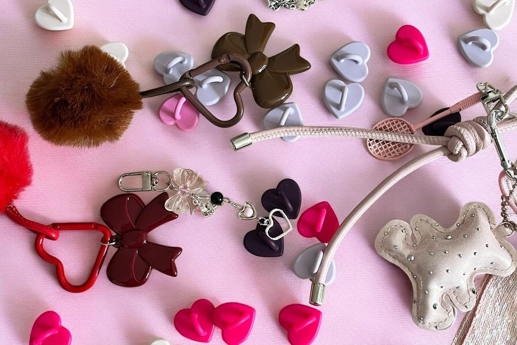 Collection of colorful keychains and charms on a pink background