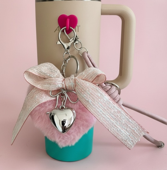 Travel mug with decorative keychain on a pink background