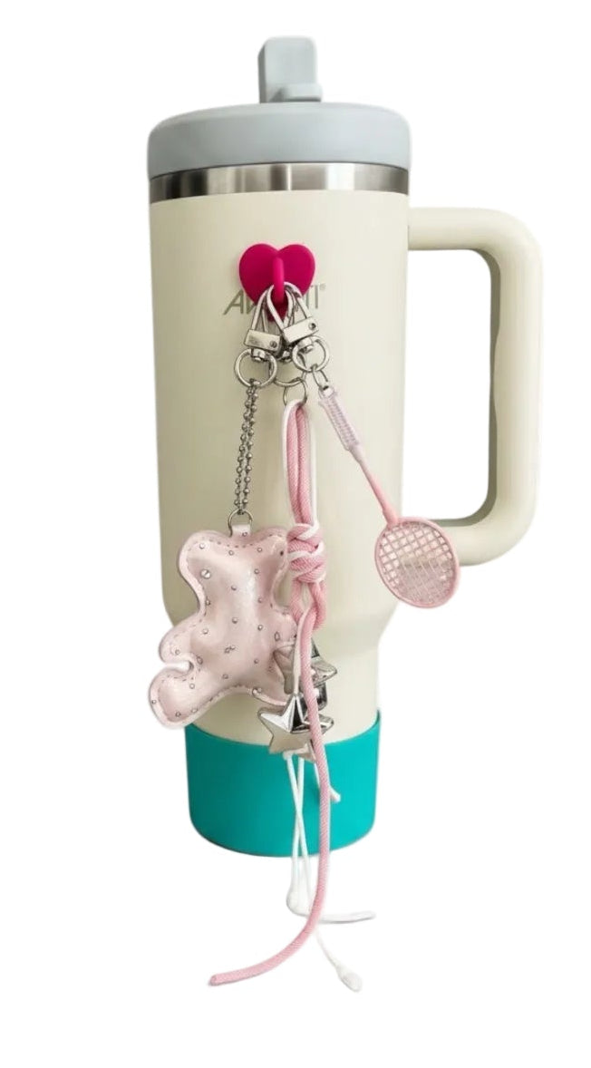 Cream-colored mug with a blue base and decorative charms on a white background